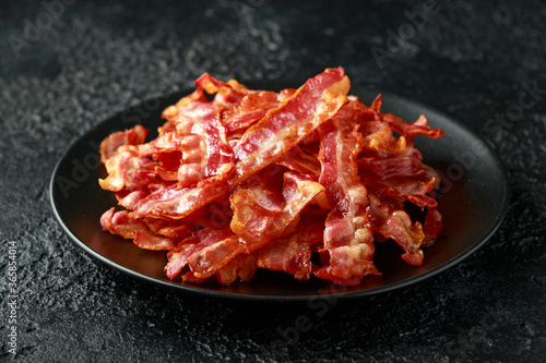 Tableau sur toile Fried crunchy Streaky Bacon pieces in a black plate