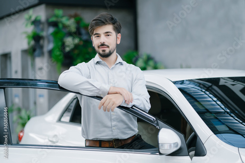 Portrait of young man opened car door and looking at camera. © edward_indy