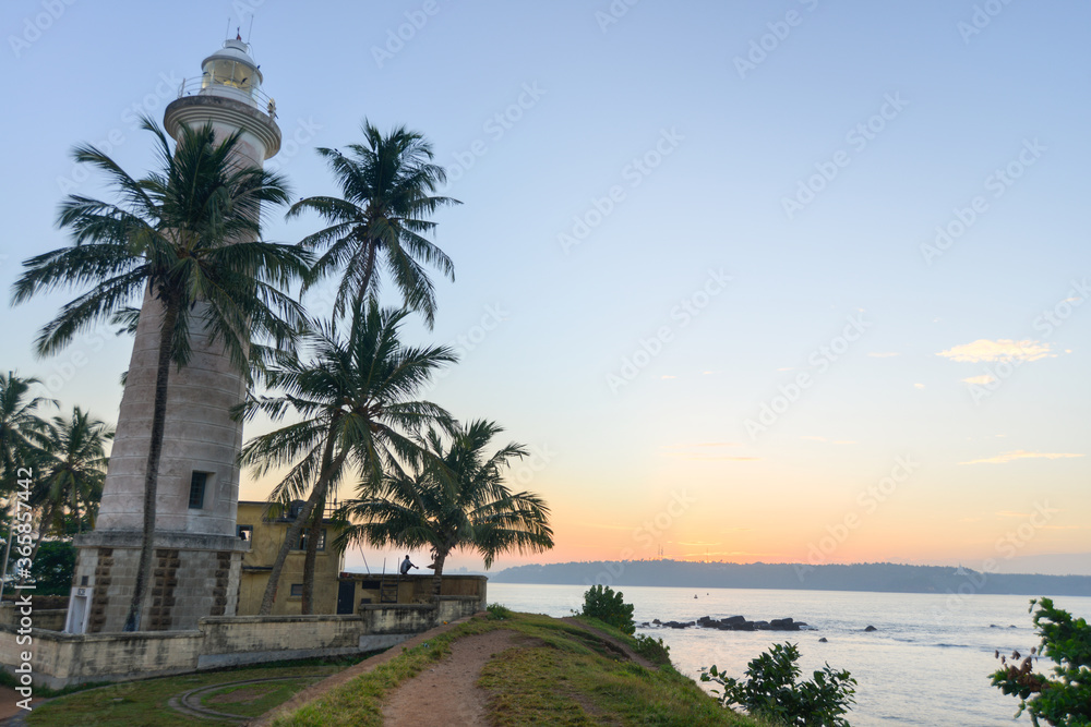 phare blanc entouré de palmier devant une mère superbe au  sud de l'ile du Sri Lanka