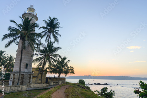 phare blanc entouré de palmier devant une mère superbe au sud de l'ile du Sri Lanka