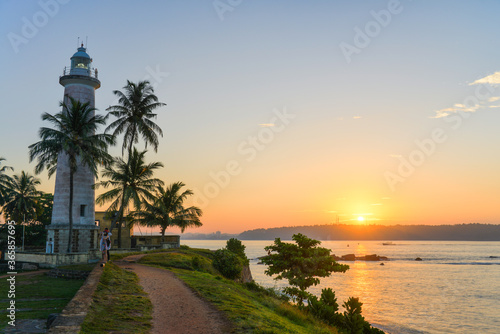 phare blanc entouré de palmier devant une mère superbe au  sud de l'ile du Sri Lanka
