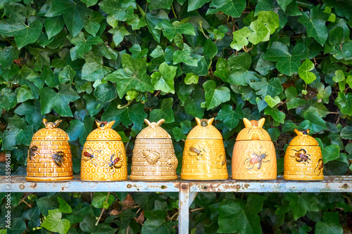 A row of vintage yellow glazed honeypots in the form of beehives in a garden.  photo