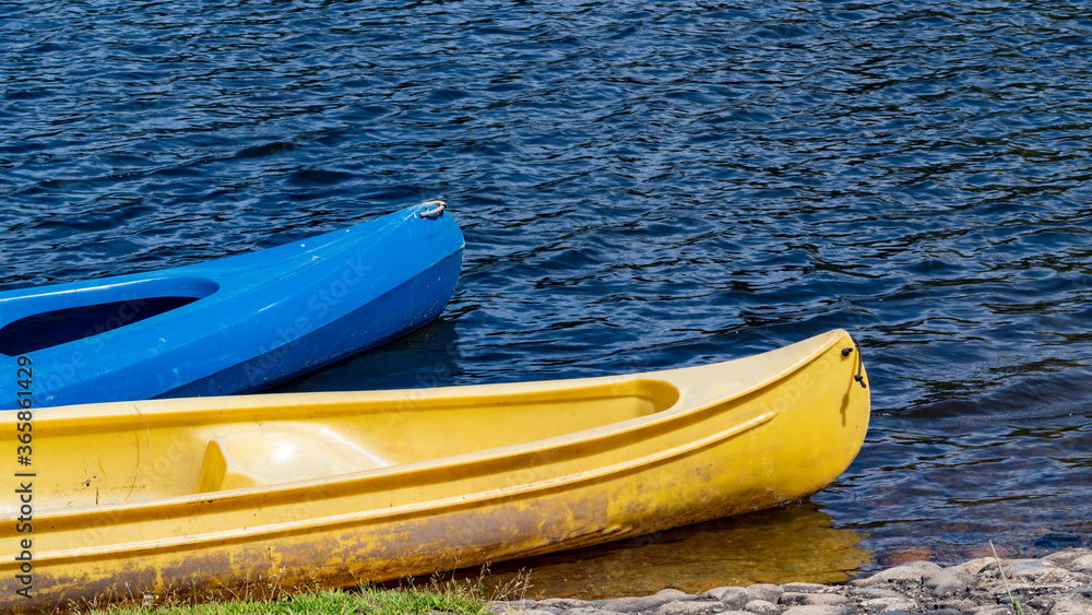 Yellow and blue kayaks on the river waiting for tourists Yellow and blue kayaks on the river waiting for tourists