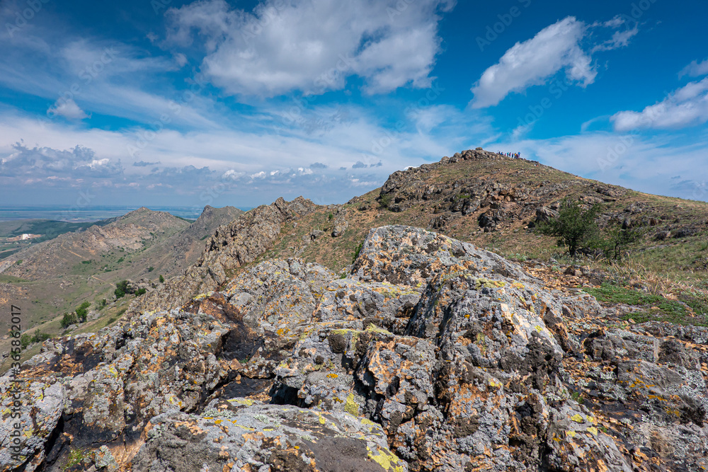 Hiking on the oldest mountains in Romania - Macin Mountains from Dobrogea region of the country - blue sky white clouds and rocks in low vegetation