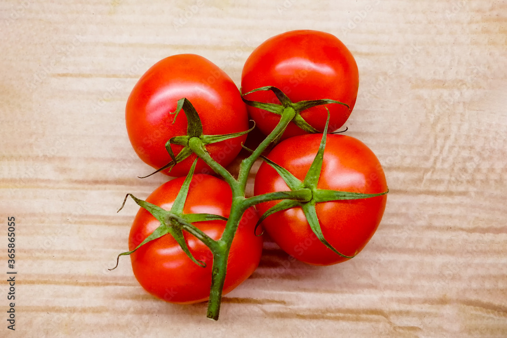 Tomatoes on a branch. View from above. Juicy and delicious vegetables on a wooden background.