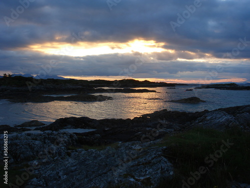 Sunset over the sea off the North West coast of Scotland near Arisaig. Cloudy and rocky islands in silhouette.