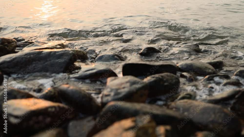 Waves hitting rocks and washing stones in during sunset. Waves hitting rocks and washing stones in during sunset.