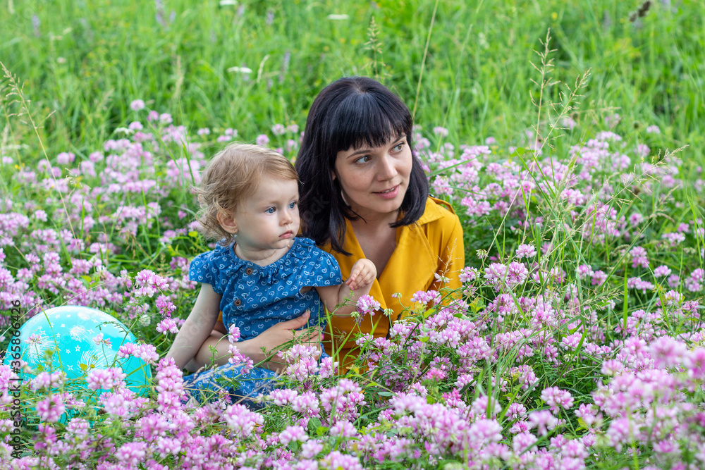 young mother with little daughter on a flower meadow in a park on a summer day young mother with little daughter on a flower meadow in a park on a summer day