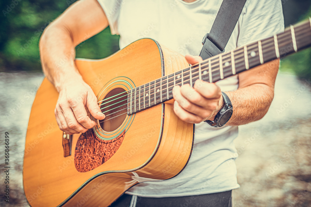 Fototapeta premium Acoustic Guitar Playing. A man plays the guitar against the background of nature.