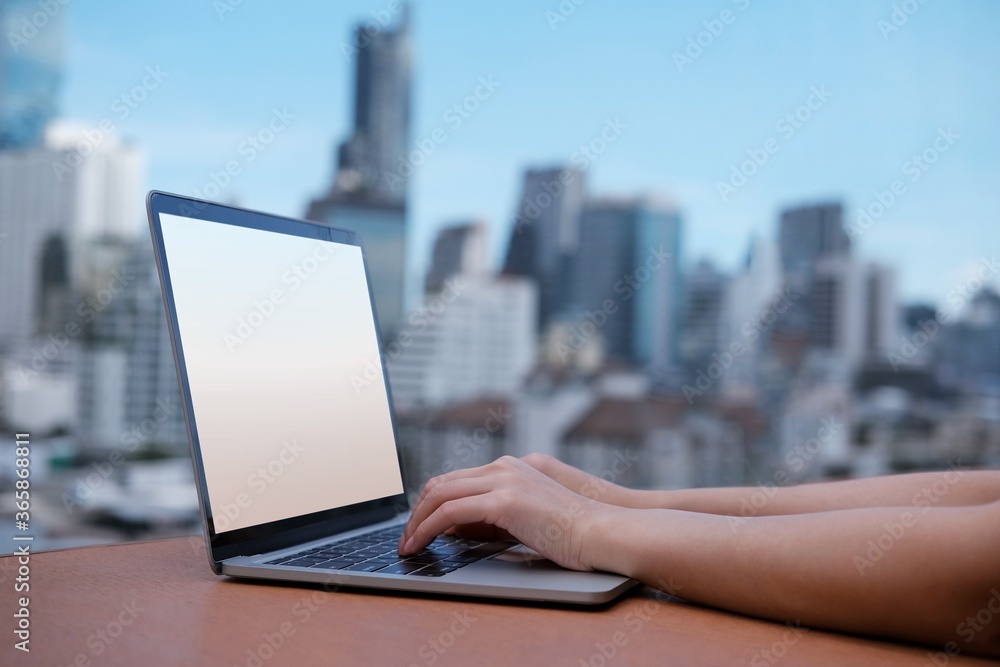 Office girl typing on white screen laptop computer, outdoor cityscape background Office girl typing on white screen laptop computer, outdoor cityscape background