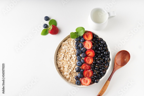 Healthy breakfast, muesli with currants, blueberries and strawberries served in bawl on light backgrund