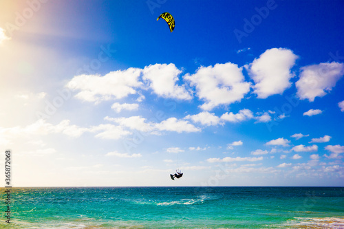 A kite surfer jumping high out the water on a windy, sunny day on the beach of the isle of Sal, Cape Verde, Africa.The amazing colors of the ocean are in contrast with the silhouette of the flying man