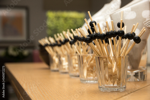 A bunch of toothpicks with little balls attached to them,to be able to hold them more easily.The little wooden sticks are nicely placed and lined up into glasses for the guests.Napkins are on the side