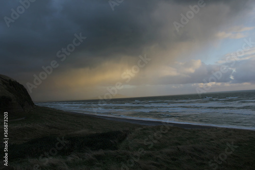 Underexposed picture of an incoming storm on the coast of New Zealand.The underexposure is a key element to the picture because it shows the threat of the storm and giving a painting-like effect.