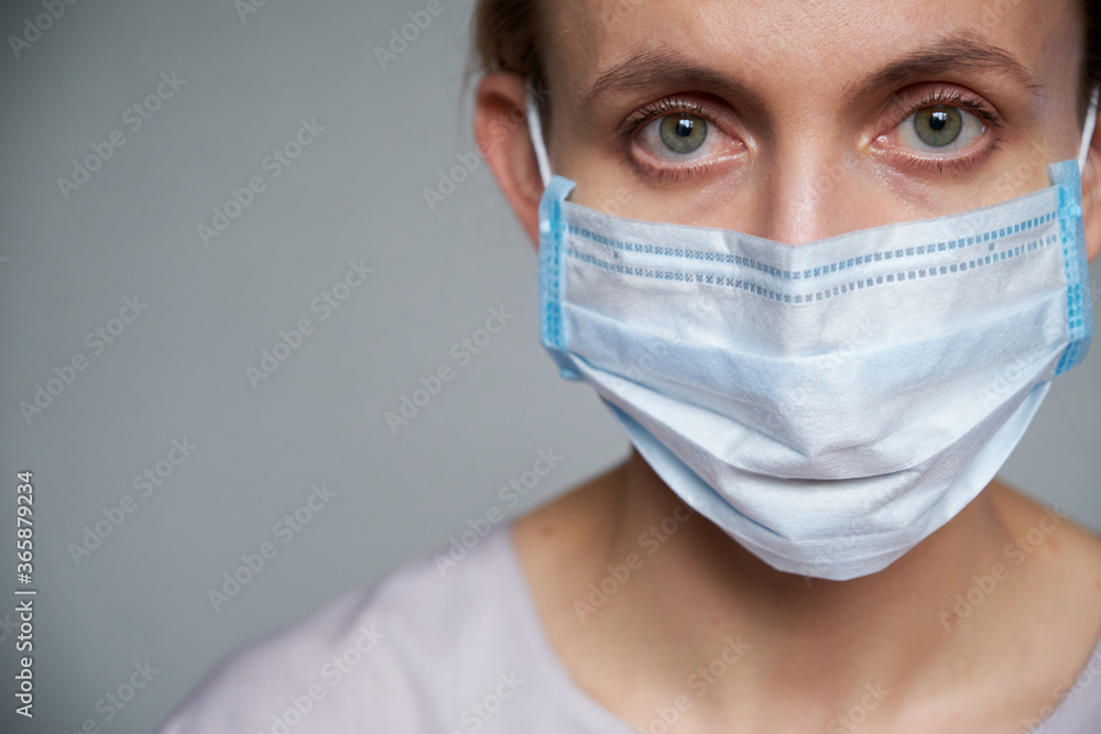 Close up of female doctor or scientist in protective medical mask over grey background