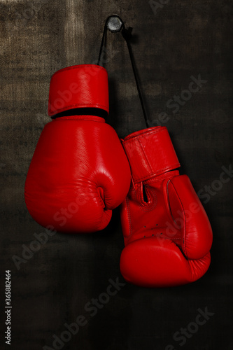 Red leather boxing gloves hanging on black wall