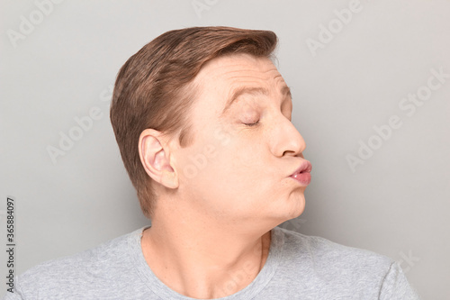 Portrait of funny mature man pouting his lips and blowing kiss