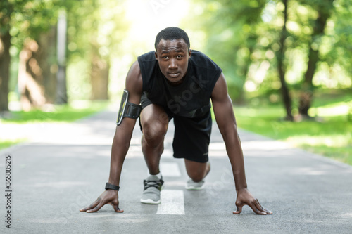 Black man jogger in ready position, training at park