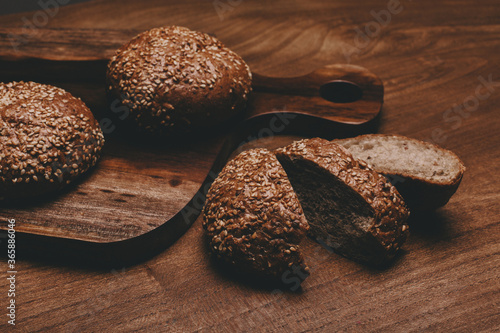 Cereal bread lie on a wooden table with a cutting board.