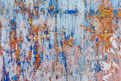 Minimalist colourful textured background of old and rusted whit, blue, brown and orange paing on metallic surface, in direct sun light in an urban environment.