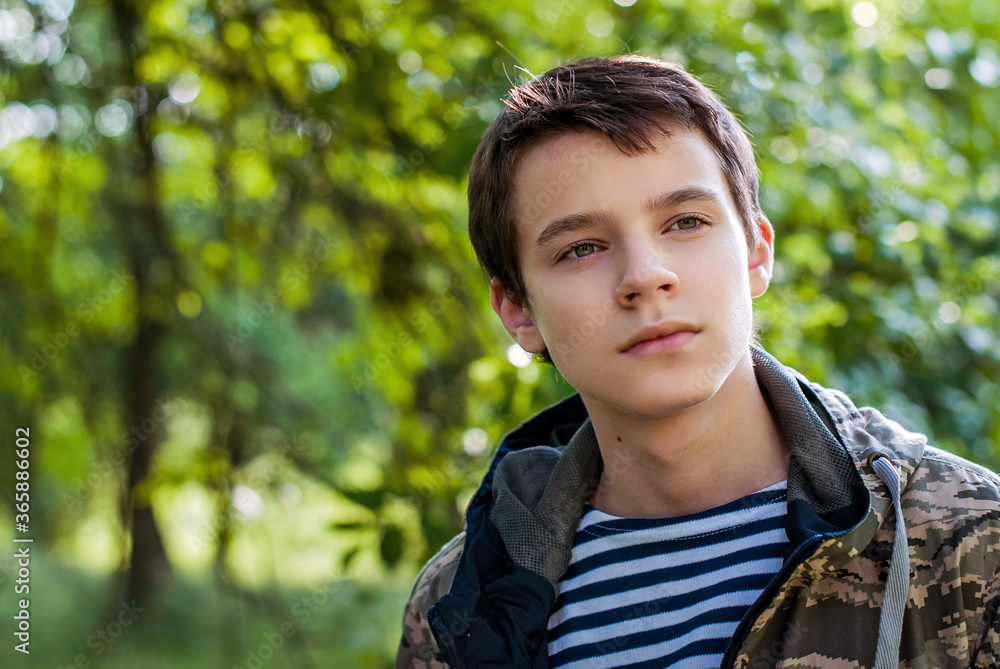 Teenager boy in a vest and camouflage jacket, portrait outdoors, looking to the side Teenager boy in a vest and camouflage jacket, portrait outdoors, looking to the side