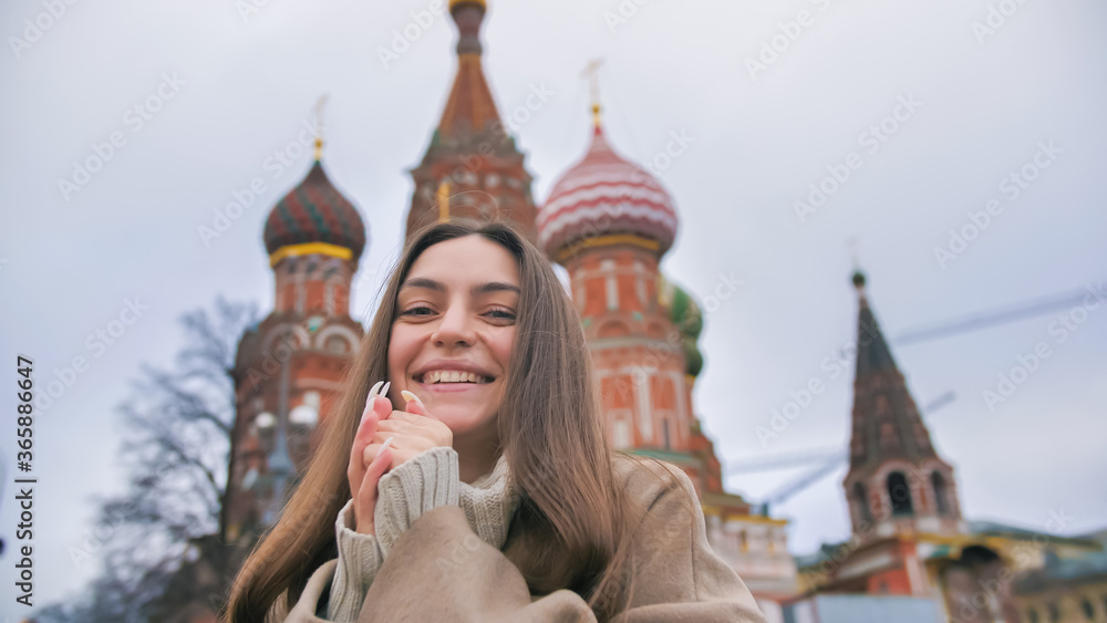 Fototapeta premium Happy smiling young woman portrait in Red Square, Moscow. A woman in the city warms her hands.