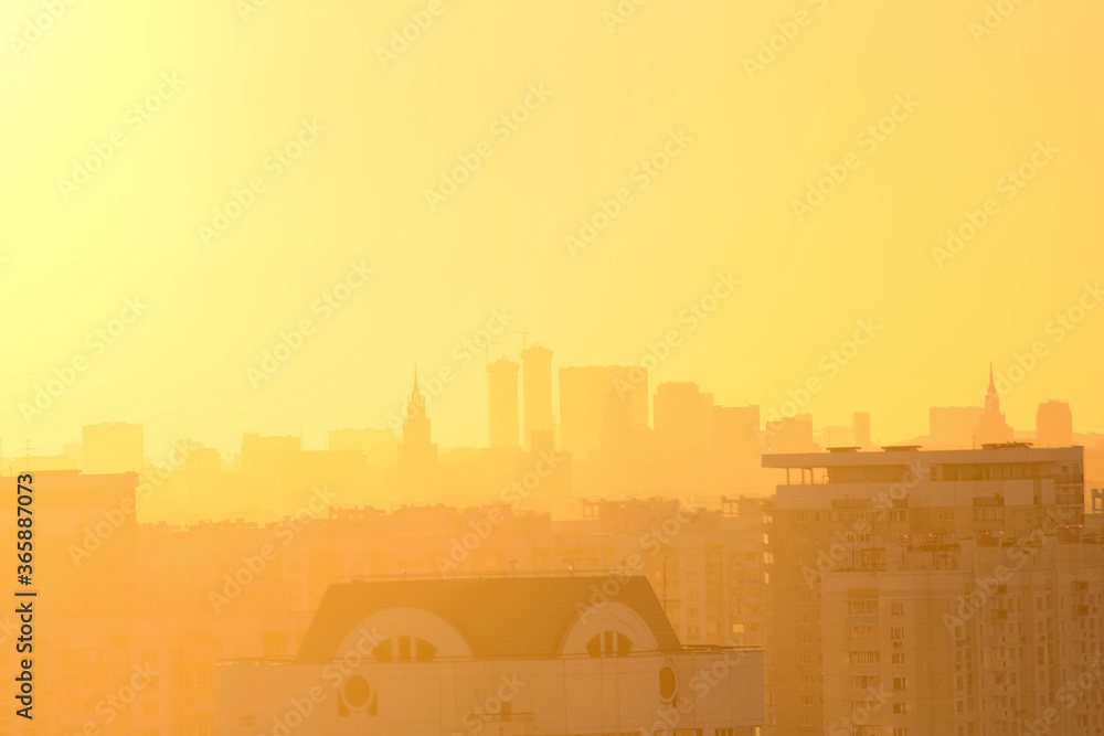Cityscape of Moscow city in Russia during golden sunset. Small haze in the air. Silhouettes of buildings are visible in the background. Golden hour theme.