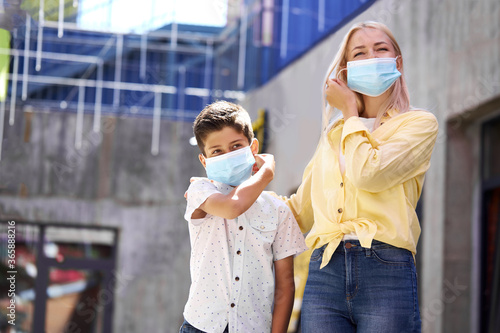 mother and child in medical masks in streets, they walk outdoors after quarantine ending. coronavirus outbreak