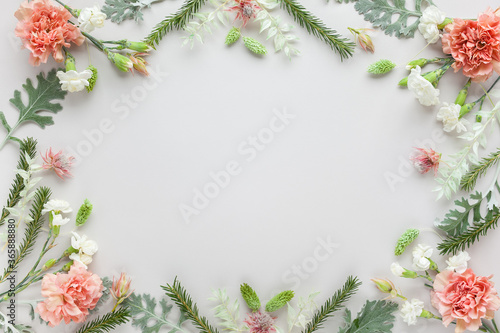 White and coral flowers and silver-green leaves on pastel grey background. Flowers composition with copy space, flat lay.