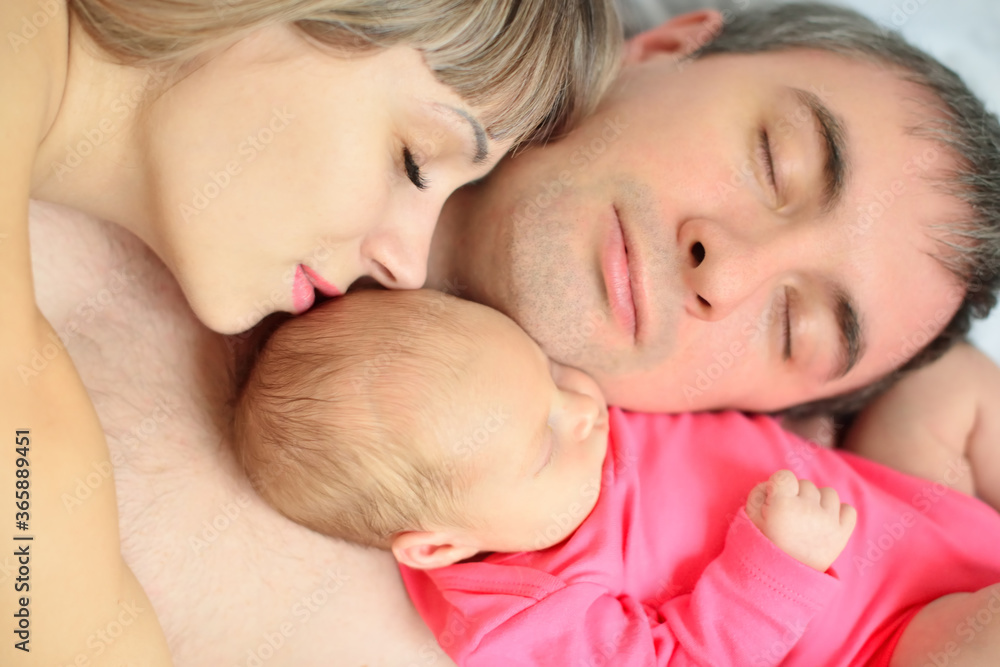 The newborn girl fell asleep with her mother and father The newborn girl fell asleep with her mother and father