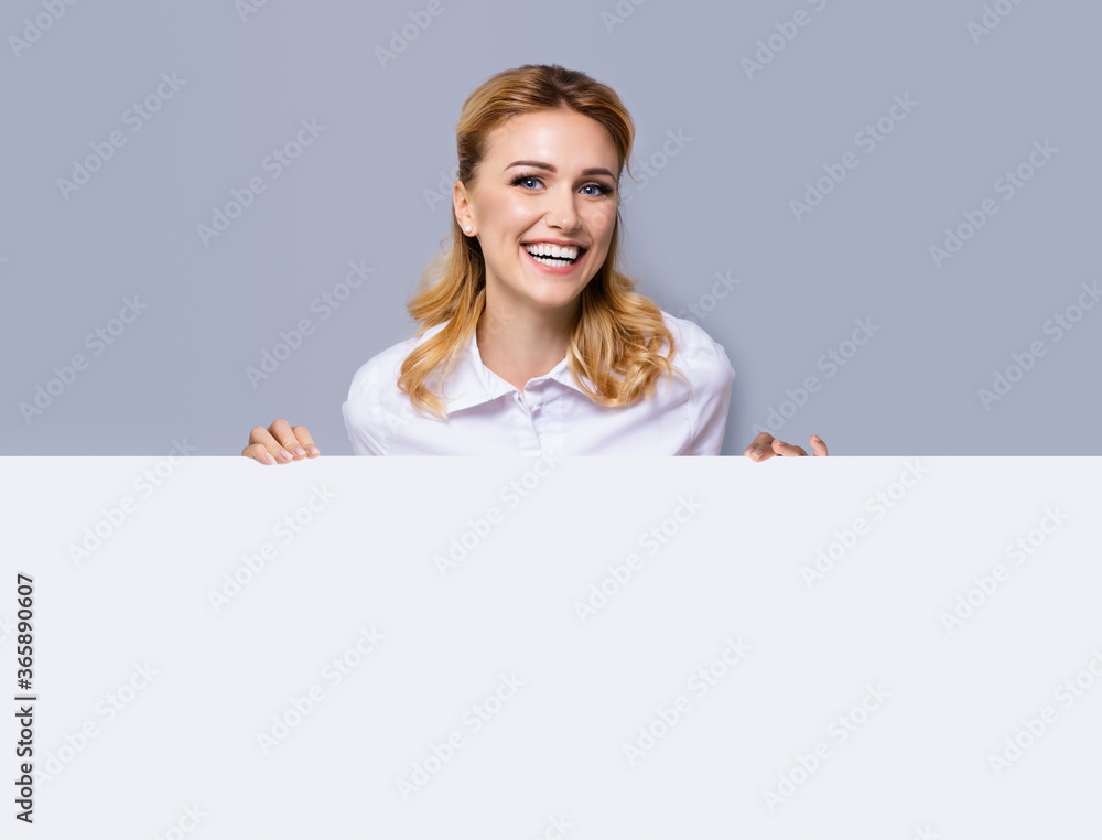 Very happy excited, laughing business woman in white confident clothing showing blank banner signboard. Success and advertising concept. Copy space empty place for some text or imaginary. Blond girl. Very happy excited, laughing business woman in white confident clothing showing blank banner signboard. Success and advertising concept. Copy space empty place for some text or imaginary. Blond girl.