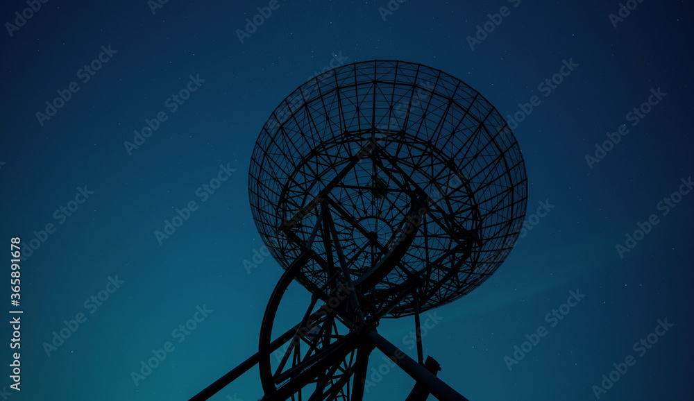 Radio telescope silhouette against abstract blue sky