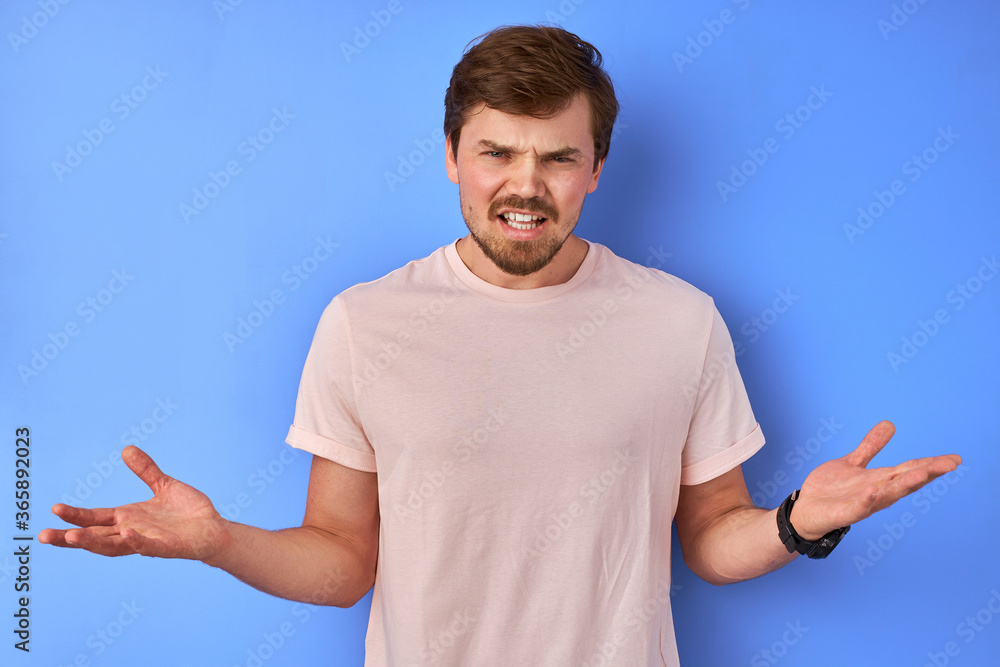 what the hell, young caucasian man in shock after getting news, he is irritated, isolated in studio, blue background what the hell, young caucasian man in shock after getting news, he is irritated, isolated in studio, blue background