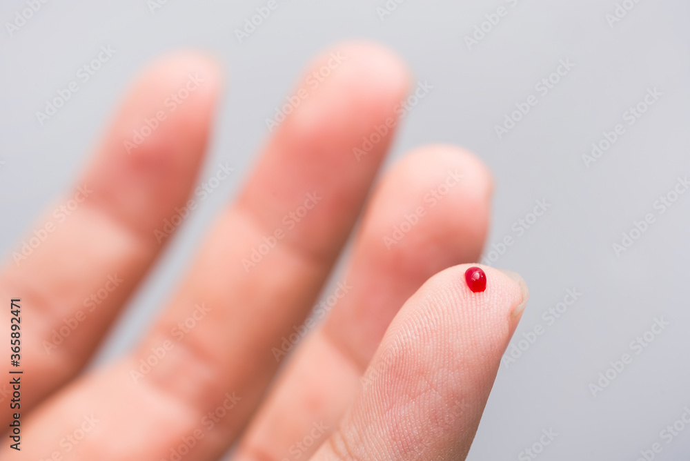 Blood drop on fingertip prepare for checking the glucose level with a glucometer for examining diabetes mellitus.