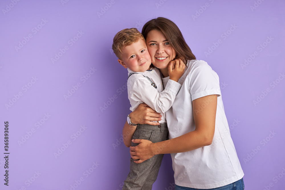 portrait of sweet caucasian child boy with mother isolated over purple background. young mom and kid hugging portrait of sweet caucasian child boy with mother isolated over purple background. young mom and kid hugging