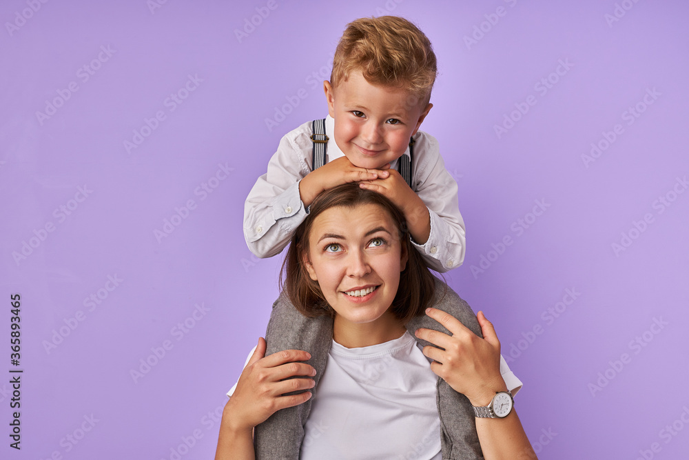 portrait of cute mother and kid boy isolated over purple background, awesome child sit on mom's neck, woman and chil in love, happy together portrait of cute mother and kid boy isolated over purple background, awesome child sit on mom's neck, woman and chil in love, happy together