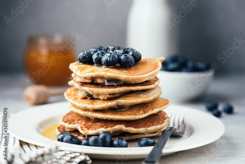 Oat pancakes with blueberries and honey on white plate. Stack of healthy vegetarian pancakes, low carb paleo pancakes