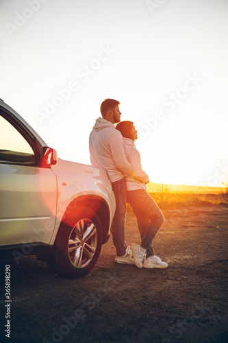 romantic moment couple looking on sunset near white suv car
