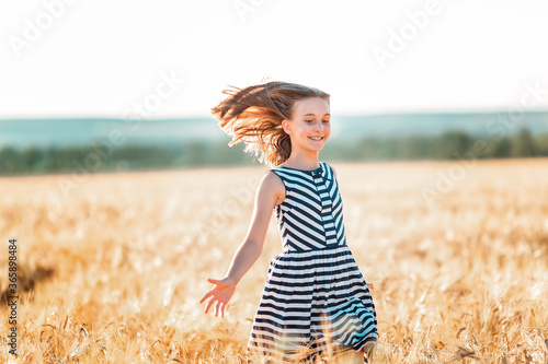 Fototapeta Naklejka Na Ścianę i Meble -  Happy teenage girl running down golden wheat field