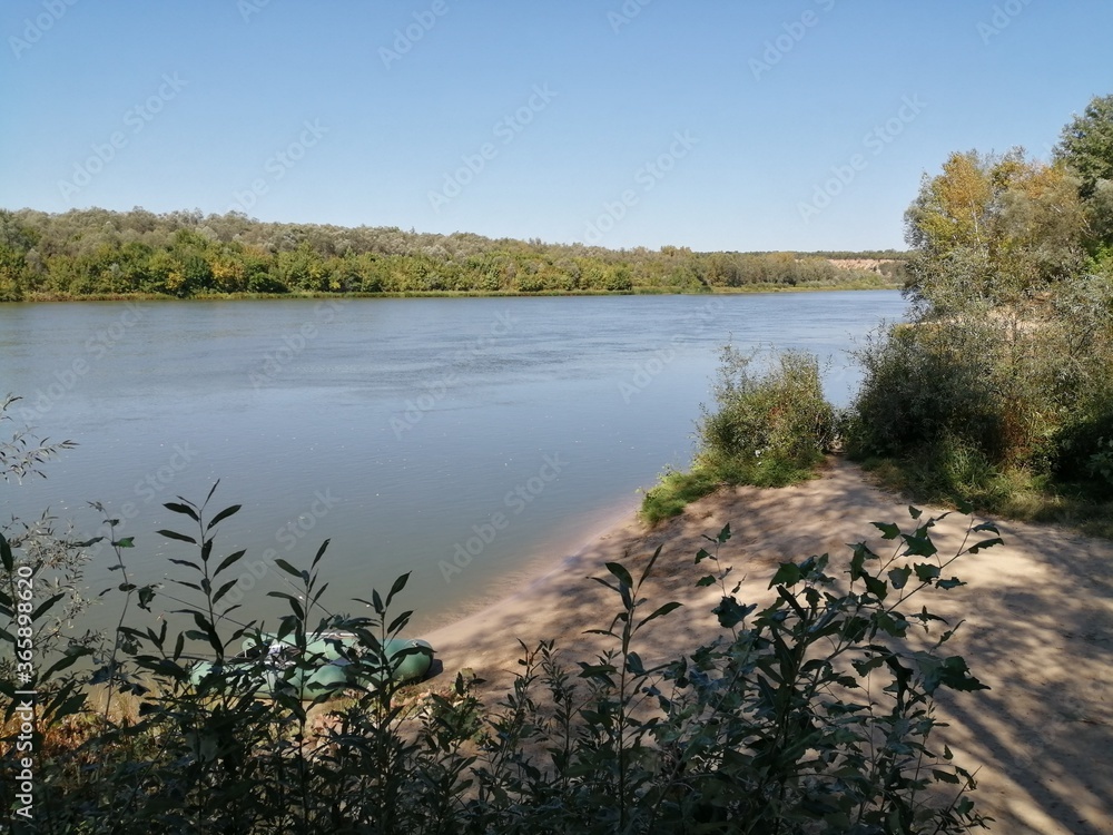 Obraz premium Rubber boat on the sandy bank of a wide river