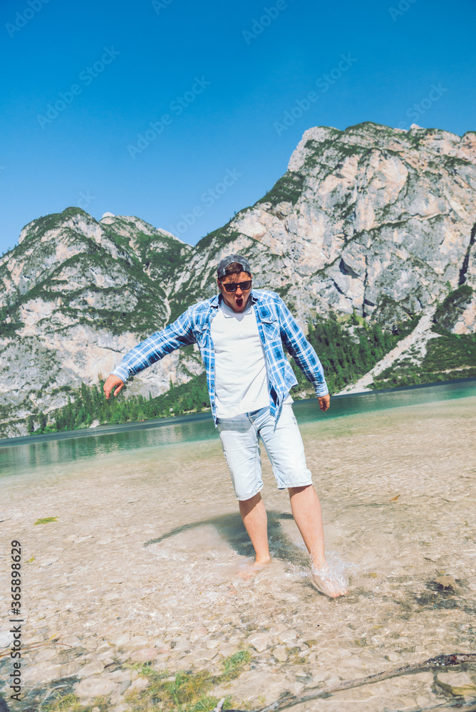 Naklejka premium man walking by lake beach mountains on background with cold water
