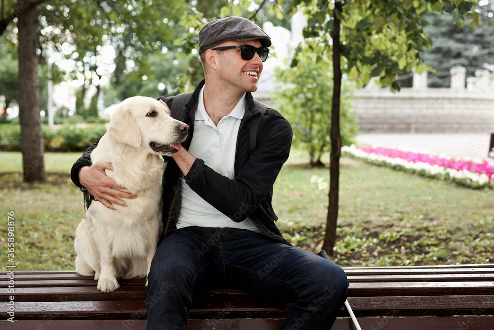 blind young man lovingly stroking guide dog, feeling gratitude for help, friend, full life of impaired, enjoying time. blind young man lovingly stroking guide dog, feeling gratitude for help, friend, full life of impaired, enjoying time.