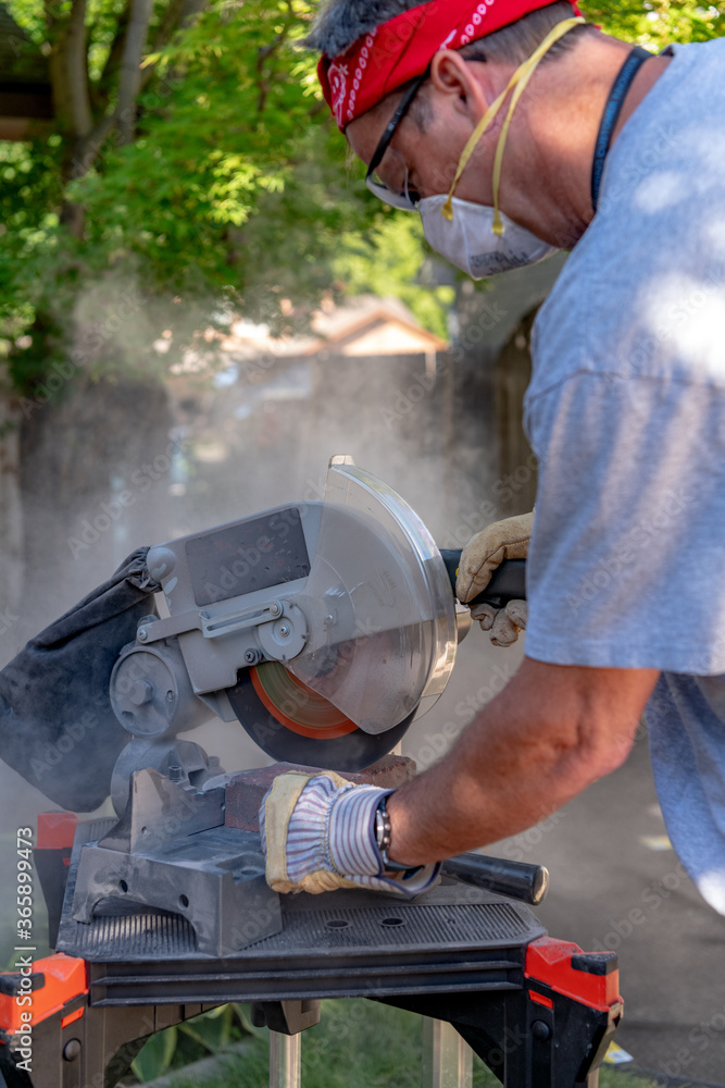 Fototapeta premium Brick layer cuts a red brick on a circular saw