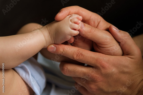 Little feet of the kid in the male hands of the dad