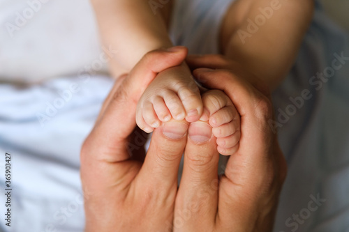 Little feet of the kid in the male hands of the dad