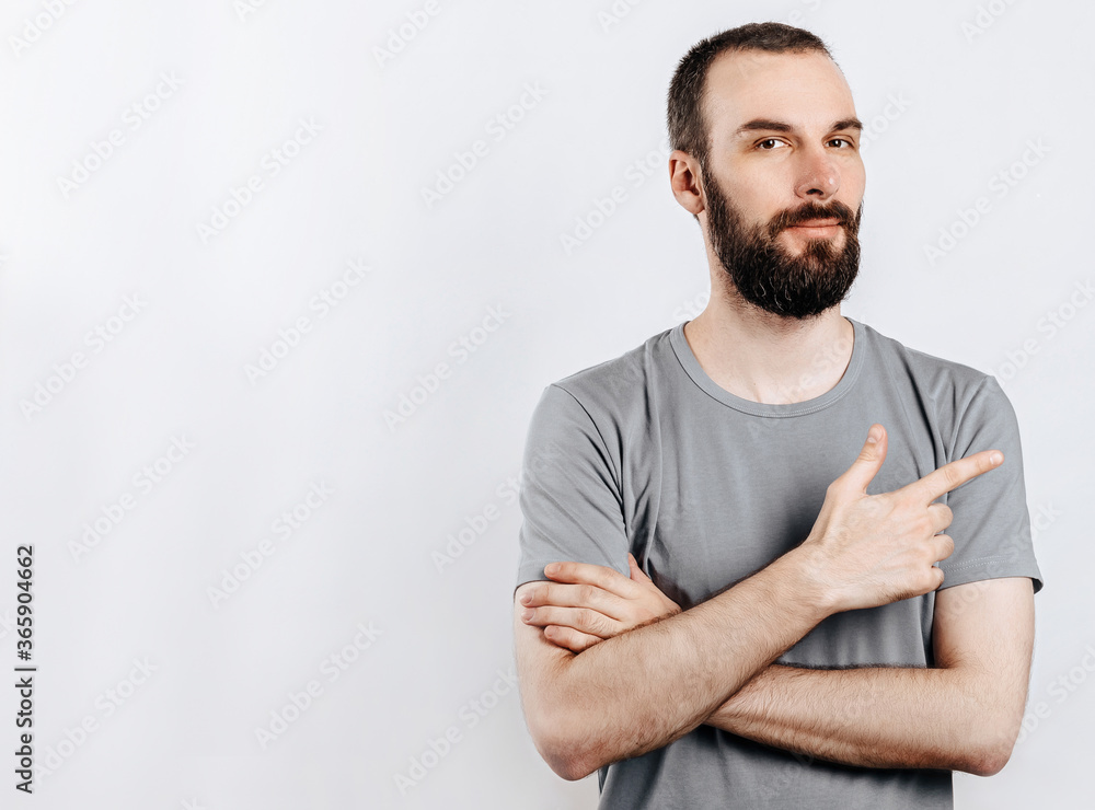 Handsome brunette man with a beard points a finger at a place for advertising on a white background Handsome brunette man with a beard points a finger at a place for advertising on a white background