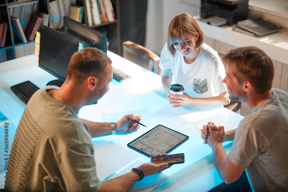Young creative team of designers developing a new interior project using tablet and phone with palette in modern studio Young creative team of designers developing a new interior project using tablet and phone with palette in modern studio