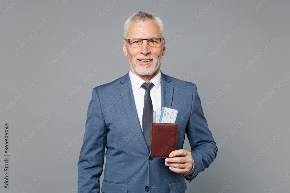 Successful elderly gray-haired mustache bearded business man in classic blue suit shirt tie isolated on grey background. Achievement career wealth business concept. Hold passport ticket boarding pass. Successful elderly gray-haired mustache bearded business man in classic blue suit shirt tie isolated on grey background. Achievement career wealth business concept. Hold passport ticket boarding pass.