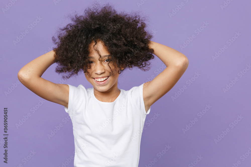 Cheerful little african american kid girl 12-13 years old in white t-shirt isolated on violet background children studio portrait. Childhood lifestyle concept. Mock up copy space. Put hands on head. Cheerful little african american kid girl 12-13 years old in white t-shirt isolated on violet background children studio portrait. Childhood lifestyle concept. Mock up copy space. Put hands on head.