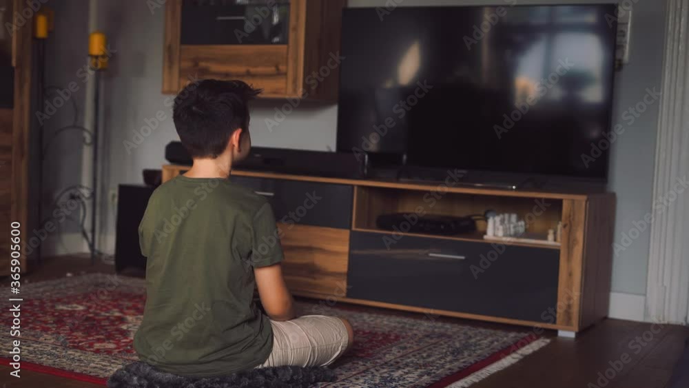 Anonymous little boy sitting in front of TV at home Anonymous little boy sitting in front of TV at home